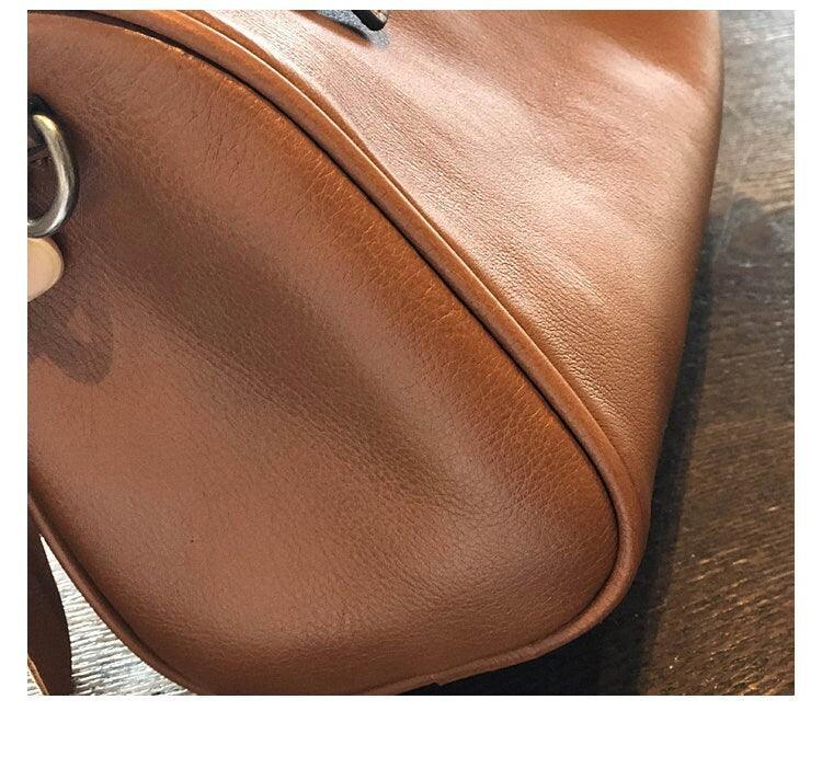 Close-up of a brown vintage leather Boston bag with smooth finish on a wooden surface