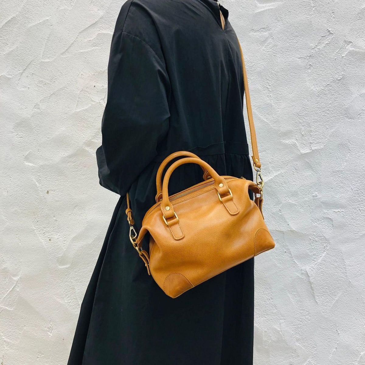 Woman carrying a brown vintage leather Boston bag with top handles and crossbody strap