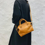 Woman carrying a brown vintage leather Boston bag with top handles and crossbody strap