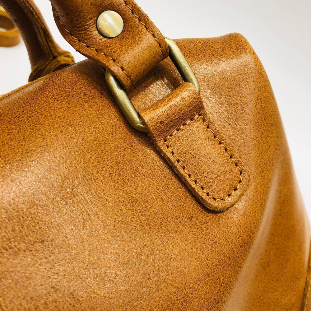 Close-up of tan vintage leather Boston bag with brass hardware and fine stitching