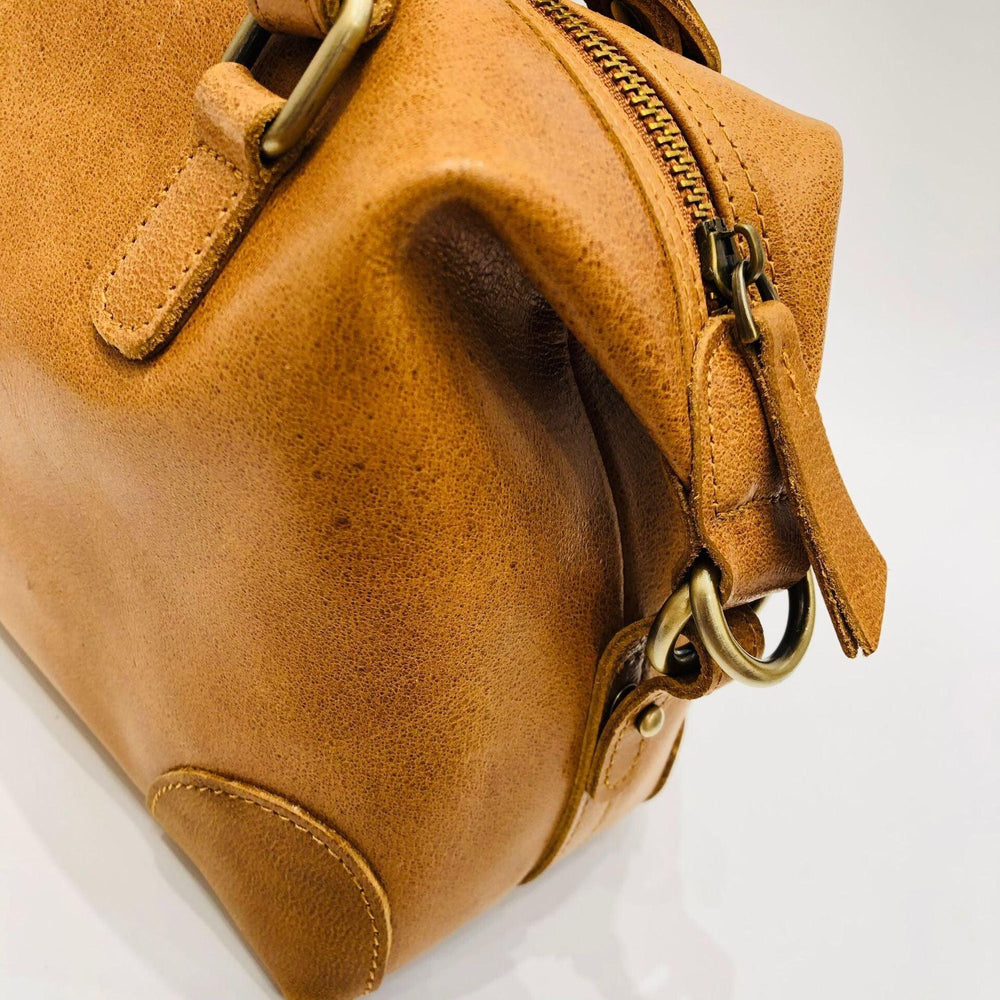 Close-up of vintage brown leather Boston bag with gold hardware and zipper detail